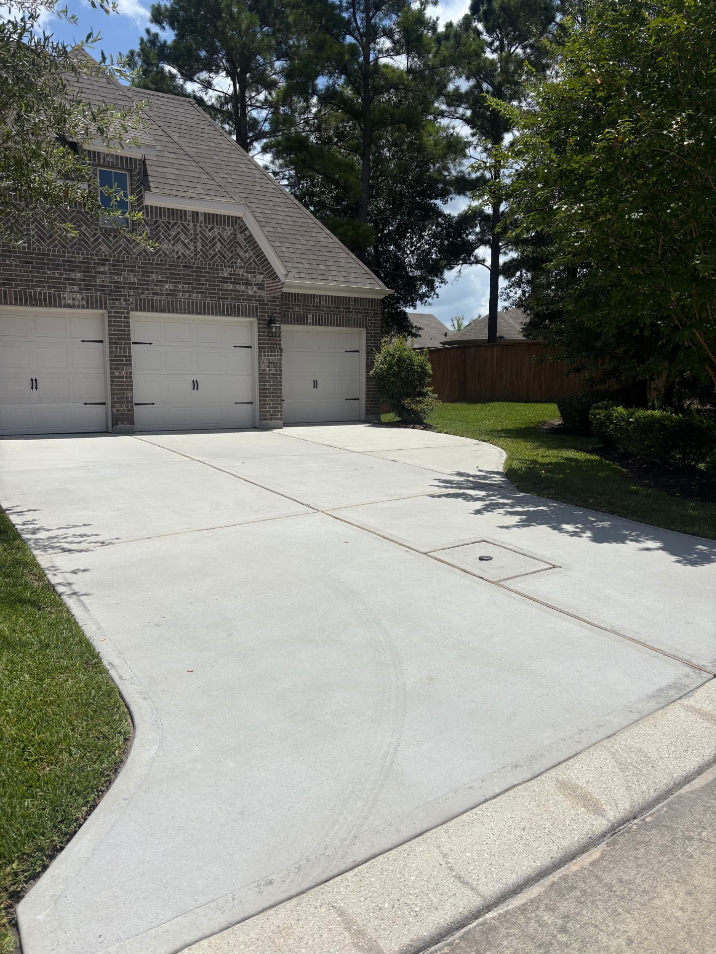Pressure washed concrete driveway at a brick home in Montgomery, TX by Integrative Services