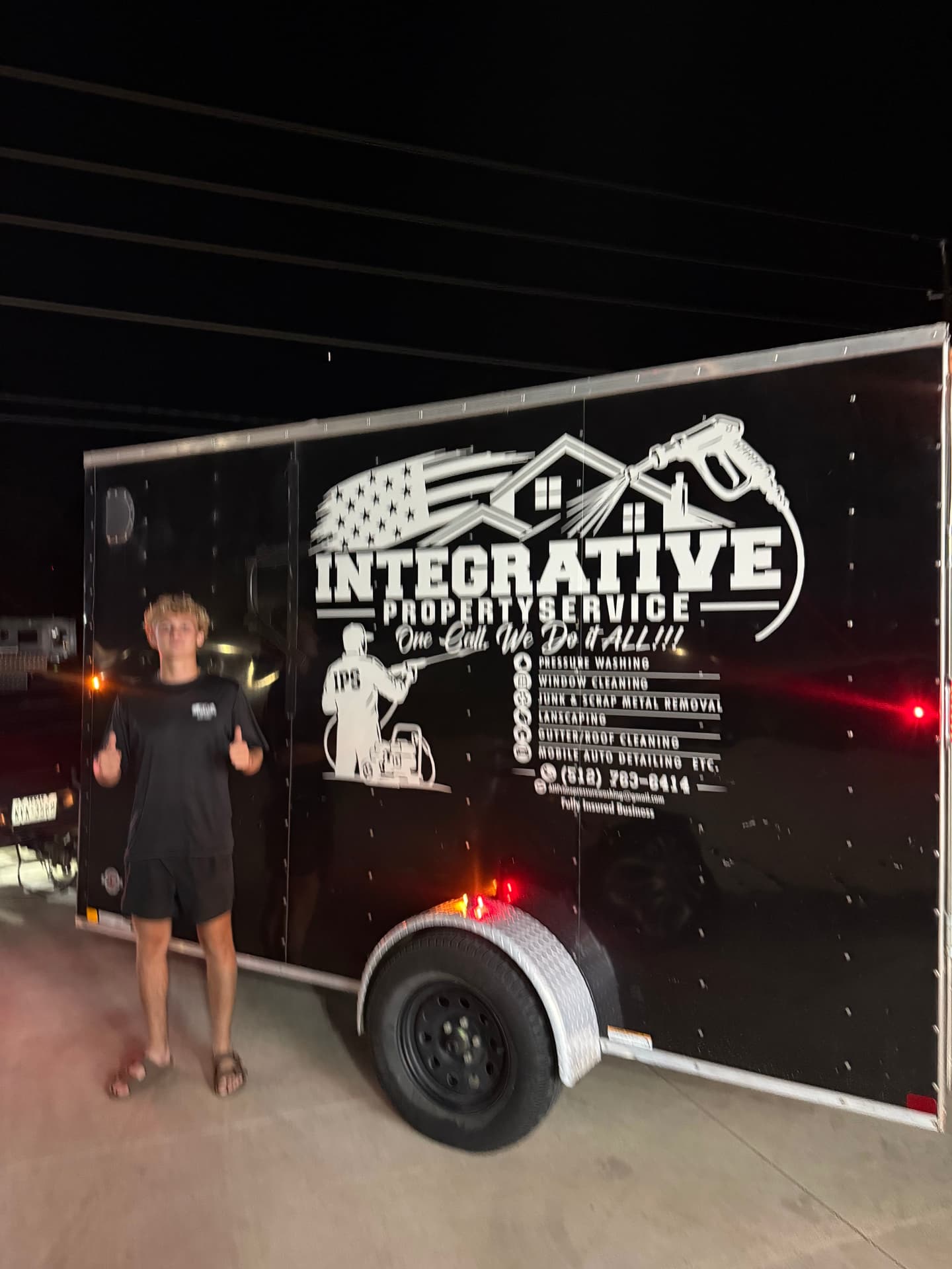 Team member giving a thumbs up next to the Integrative trailer at night — Integrative Services, Montgomery TX