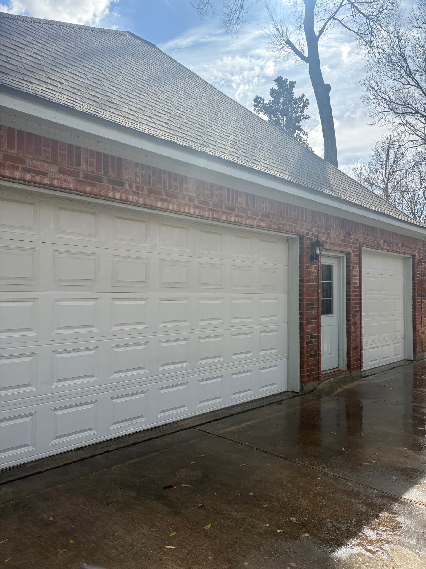 Brick home with white garage doors and a freshly washed wet driveway — Integrative Services, Montgomery TX